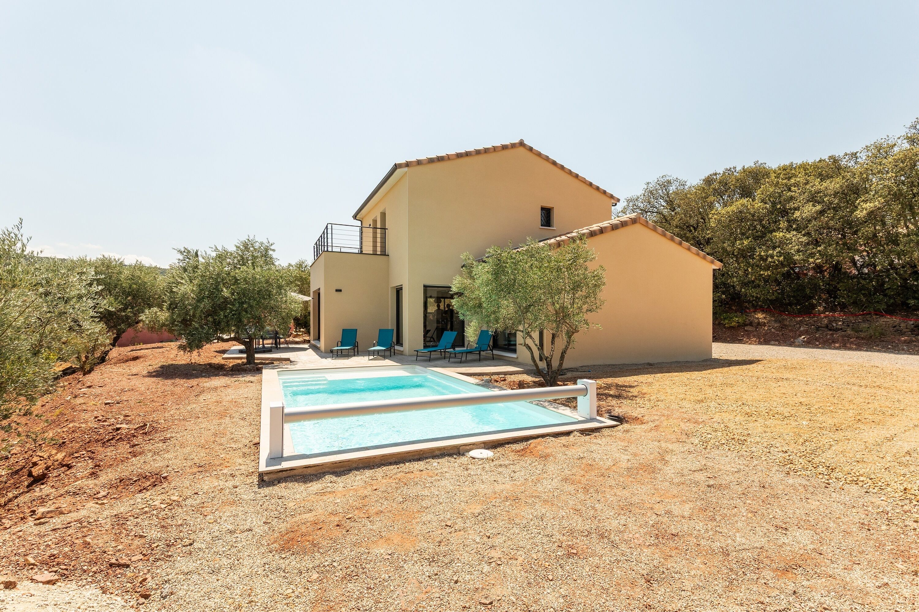 A modern house with a swimming pool, outdoor seating, and a garden.