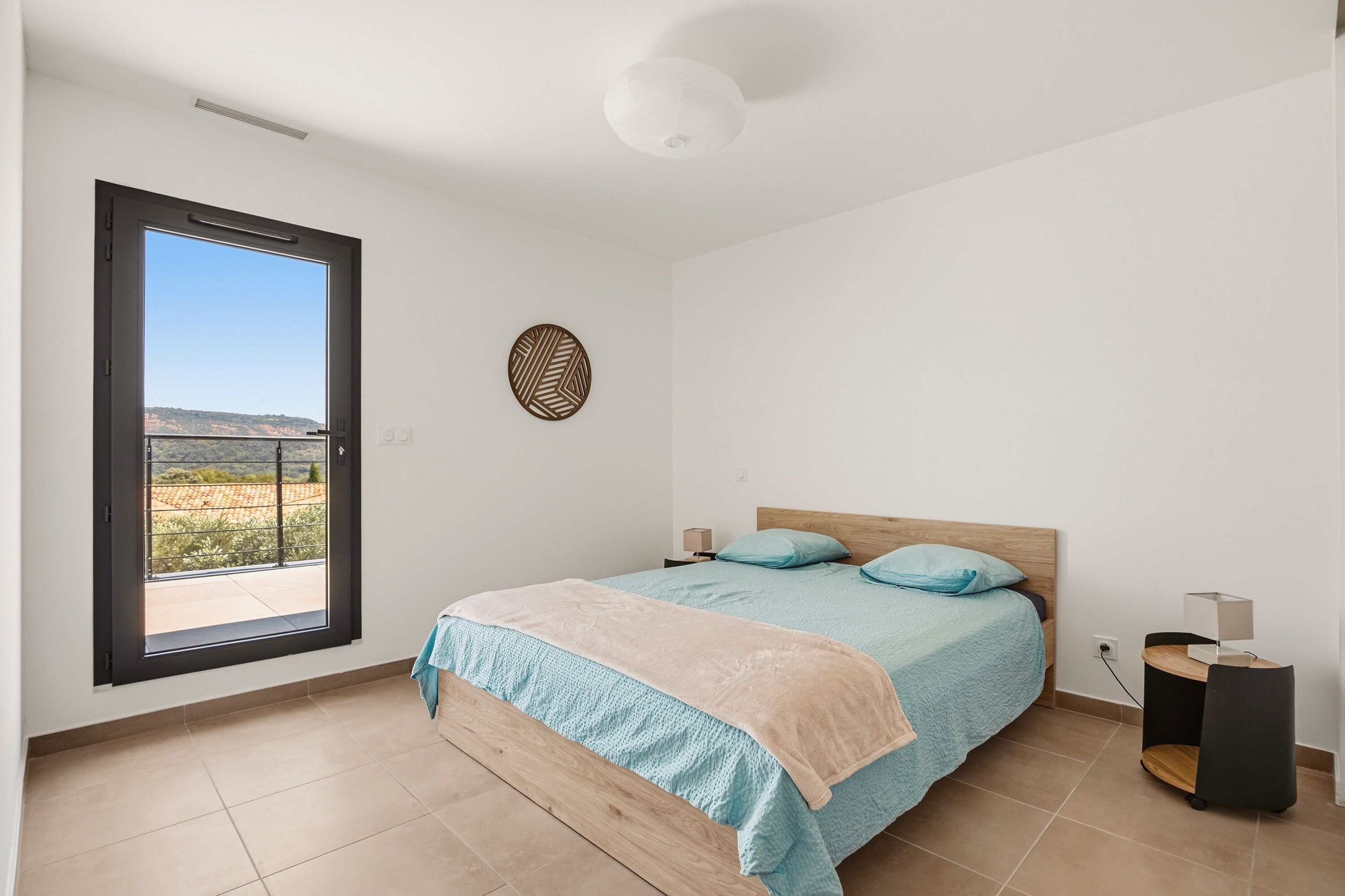 Una camera da letto con un letto, una finestra, una lampada a soffitto e vista sull'esterno.