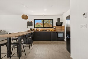 Eine moderne Küche mit Essbereich, ausgestattet mit einem großen Fenster, schwarzen Schränken und einem eingebauten Backofen.