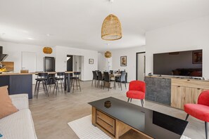 Ein stilvoller Wohnraum mit Essbereich, Küche und einem großen Flachbildfernseher.