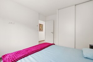 Ein Schlafzimmer mit einem Bett, einem Kleiderschrank und einer Tür zu einem anderen Raum.