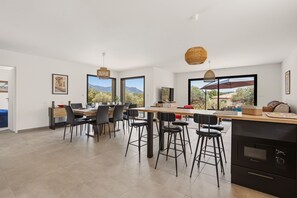 Une cuisine moderne avec un coin repas, de grandes fenêtres et une vue sur l’extérieur.