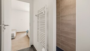 A hallway with a white door, a radiator, and a bed in the adjacent room. - Maison de la Seranne - Avec piscine (Le Bosc)