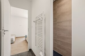 A hallway with a white door, a radiator, and a bed in the adjacent room. - Maison de la Seranne - Avec piscine (Le Bosc)