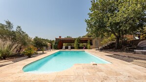 A rectangular swimming pool with a pergola structure overhead, surrounded by stone tiles and greenery. - Maison de la Seranne - Avec piscine (Le Bosc)