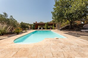 A rectangular swimming pool with a pergola structure overhead, surrounded by stone tiles and greenery. - Maison de la Seranne - Avec piscine (Le Bosc)
