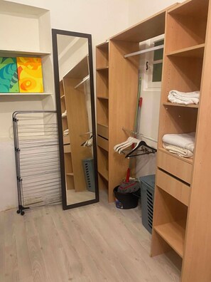 Garderobeskab med åbne hylder, et tøjstativ og en kost.