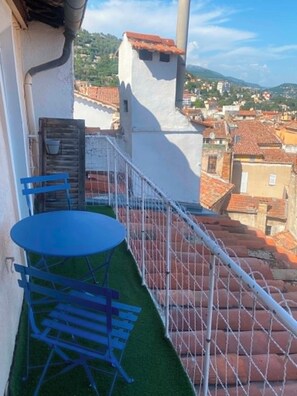 Ein Balkon mit Tisch und Stühlen, ein kleiner Gartenbereich und Blick auf die Stadt.
