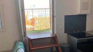 Huoneessa on puinen tikapuu, joka johtaa parvekkeelle, jalustalla oleva televisio ja roskakori.