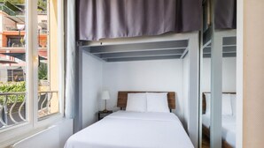 Quarto com cama, mesa de cabeceira, luminária, janela e vista para o exterior.