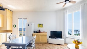 Uma cozinha moderna com área de jantar, TV e vista para o mar.
