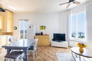 A modern kitchen with a dining area, a TV, and a view of the sea. - Le balcon d'Anselmetti - Proche Plage (Cap-d'Ail)