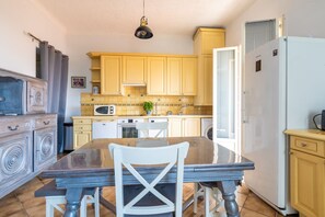 A kitchen with a dining table, chairs, a microwave, and a refrigerator. - Le balcon d'Anselmetti - Proche Plage (Cap-d'Ail)
