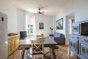 A well-lit living space with a dining area, a sofa, a television, and a ceiling fan. - Le balcon d'Anselmetti - Proche Plage (Cap-d'Ail)