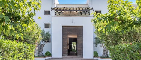 A modern building with a central entrance, surrounded by greenery.