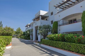 Ein modernes Mehrfamilienhaus mit Balkonen, einem gepflasterten Einfahrt und einer gepflegten Grünanlage.