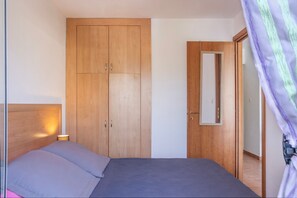 Ein Schlafzimmer mit Bett, Kleiderschrank und einer Tür mit Spiegel.