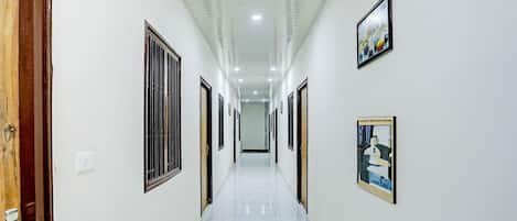 A corridor with doors on both sides, a tiled floor, and framed artwork on the walls.
