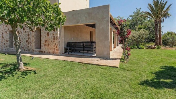 Ein modernes Haus mit überdachter Terrasse und gepflegtem Rasen.