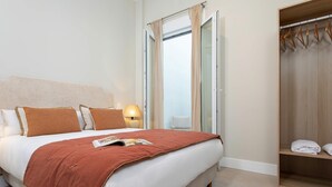 A hotel room with a bed, a nightstand, a lamp, a window with curtains, and a wardrobe. - Genteel Home San Anton 101 (Granada)