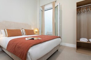A hotel room with a bed, a nightstand, a lamp, a window with curtains, and a wardrobe. - Genteel Home San Anton 101 (Granada)