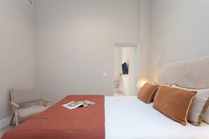 A hotel room with a bed, a chair, a lamp, and a television on the wall. - Genteel Home San Anton 101 (Granada)