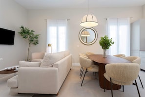 A modern living room with a sofa, dining table, chairs, and a TV. - Genteel Home San Anton 102 (Granada)