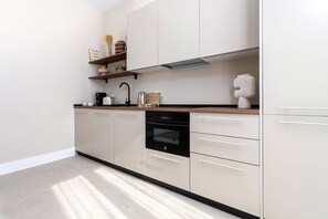 A modern kitchen with white cabinetry, a dishwasher, and a coffee machine. - Genteel Home San Anton 103 (Granada)