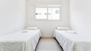 Et lille, rent værelse med to senge, et vindue og klinkegulv.