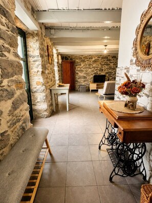 A cozy room with stone walls, a wooden bench, a TV, and a decorative mirror.
