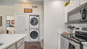 A compact kitchen with a microwave, oven, and stacked washer-dryer unit. - Cozy Kissimmee Getaway Near Orlando Attractions (Kissimmee)