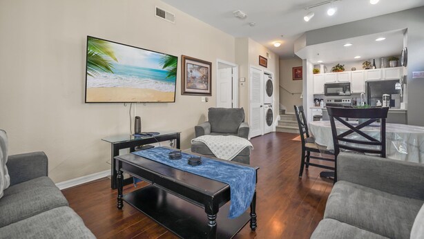 A living room with a coffee table, two armchairs, a TV, and a kitchen in the background. - Cozy Kissimmee Getaway Near Orlando Attractions (Kissimmee)