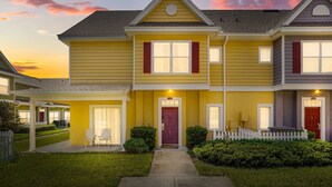 A two-story residential building with a front porch, a red door, and a white picket fence. - Cozy Kissimmee Getaway Near Orlando Attractions (Kissimmee)