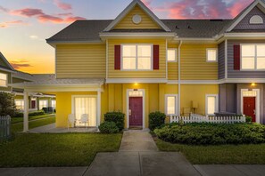 A two-story residential building with a front porch, a red door, and a white picket fence. - Cozy Kissimmee Getaway Near Orlando Attractions (Kissimmee)