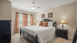 A bedroom with a bed, two bedside lamps, a ceiling fan, and a window with curtains. - Cozy Kissimmee Getaway Near Orlando Attractions (Kissimmee)