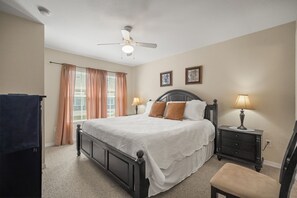 A bedroom with a bed, two bedside lamps, a ceiling fan, and a window with curtains. - Cozy Kissimmee Getaway Near Orlando Attractions (Kissimmee)