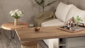 Un espace de vie moderne comprenant une table à manger en bois, un canapé et une petite table d’appoint agrémentée d’un vase de fleurs.