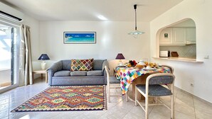 Ein Wohnzimmer mit Sofa, einem Couchtisch mit Speisen, einem Teppich und einem Strandbild.