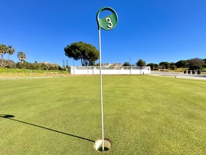 A golf course with a green flag labeled '3' on a pole, surrounded by a well-maintained lawn and a white fence in the background. - Albufeira Balaia Golf Vilage 8 by Homing (Albufeira)