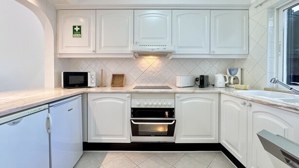 Eine moderne Küche mit weißen Schränken, einer Mikrowelle, einem Toaster und einem Backofen.