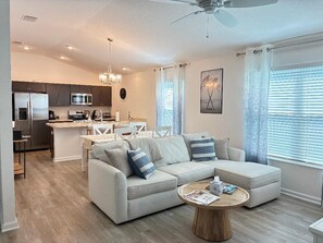 Un salon moderne avec un canapé, une table basse et un coin cuisine à l’arrière-plan.