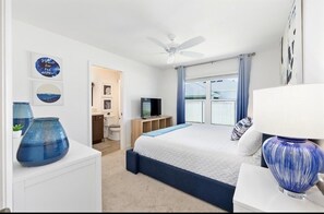 Une chambre à coucher avec un lit, un ventilateur de plafond, une télévision et des œuvres d’art accrochées aux murs.
