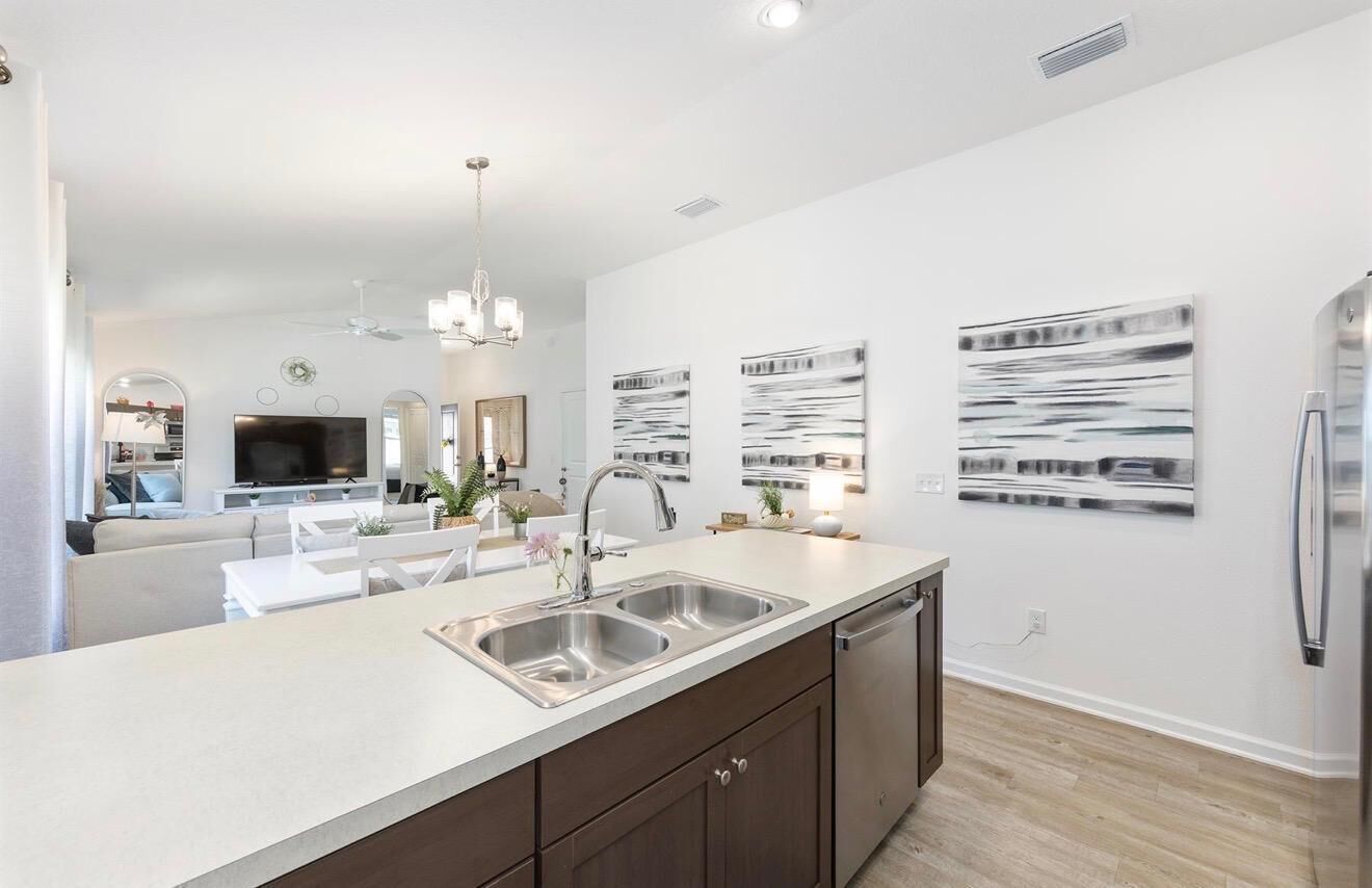 A modern kitchen with a central island, stainless steel appliances, and artwork on the walls.