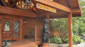 En entré till en stuga byggd av trä, med en björnstaty, en kristallkrona och en skylt med texten ”Big Bear Lodge”.
