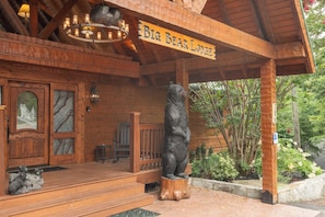 Eingang eines Holzgebäudes mit einer Bär-Statue, einem Chandelier und einem Schild, auf dem 'Big Bear Lodge' steht.