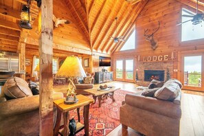 A lodge interior with a fireplace, wooden ceiling, and a large window. - Big Bear Lodge - 7BR Mtn Retreat, Theater & Hot Tub (Sevierville)