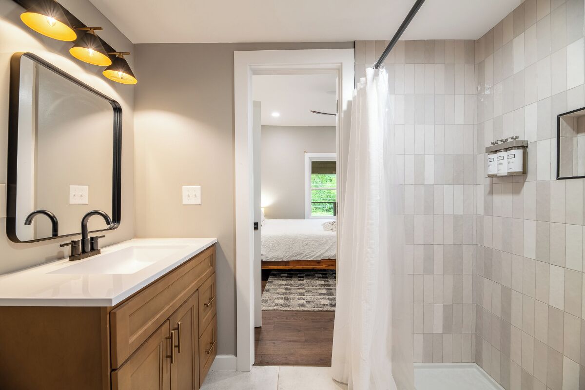 A bathroom with a large mirror, a sink, and a shower area.