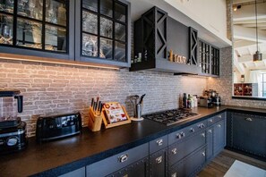 A kitchen with a brick wall, a gas stove, a toaster, and a knife block. - Vue imprenable, à 5 min à pied du village. (Saint-Rémy-de-Provence)