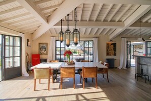 A dining area with a high ceiling and exposed beams, a table with chairs, and a view of the outdoors. - Vue imprenable, à 5 min à pied du village. (Saint-Rémy-de-Provence)