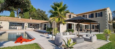Et moderne hus med swimmingpool, udendørs møbler og en velplejet have.